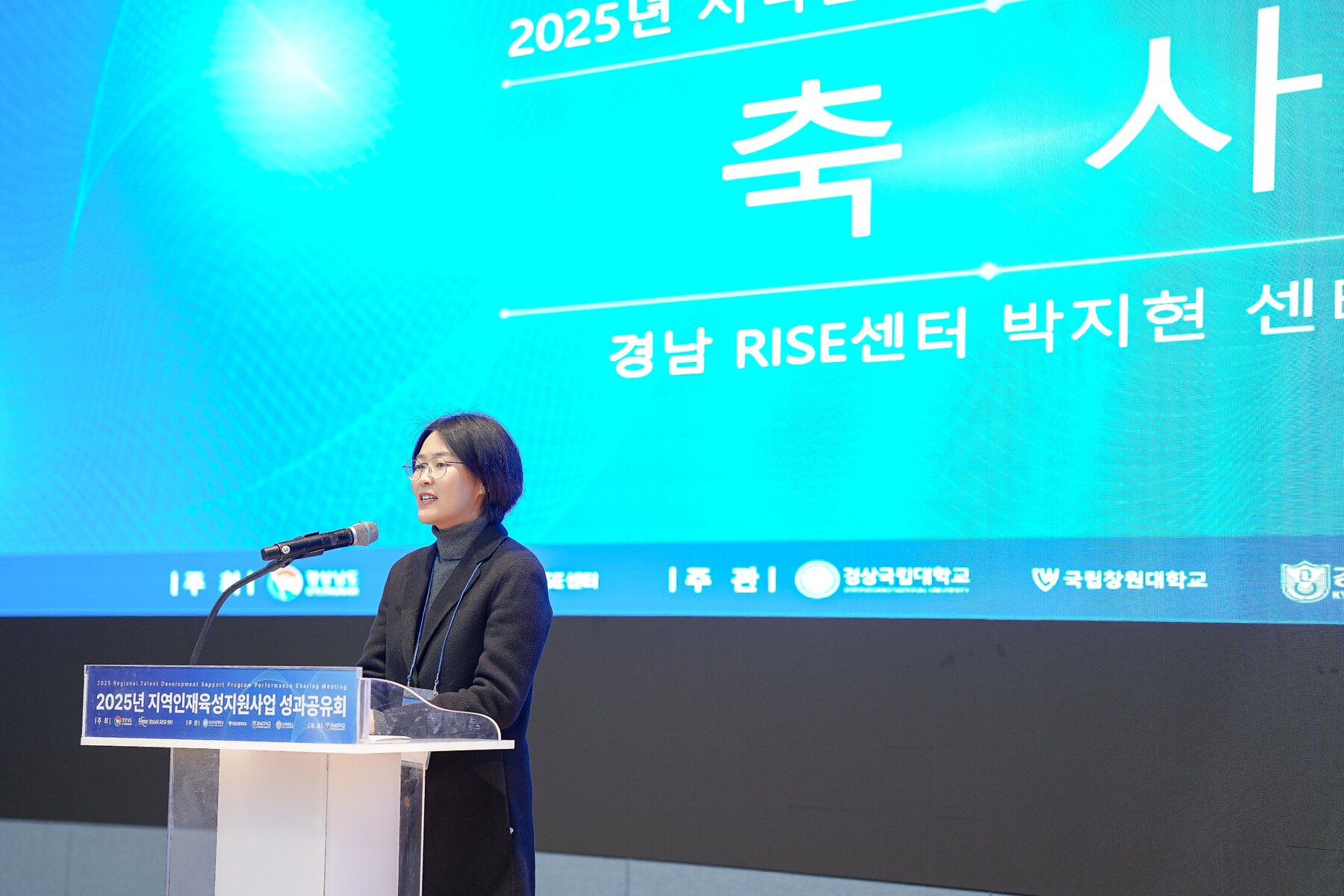 실내 포럼에서 축사가 진행되는 무대와 영상